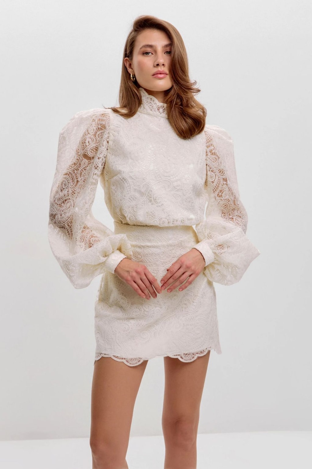 Model wearing the ivory lace blouse bloused over the matching lace mini skirt, front view