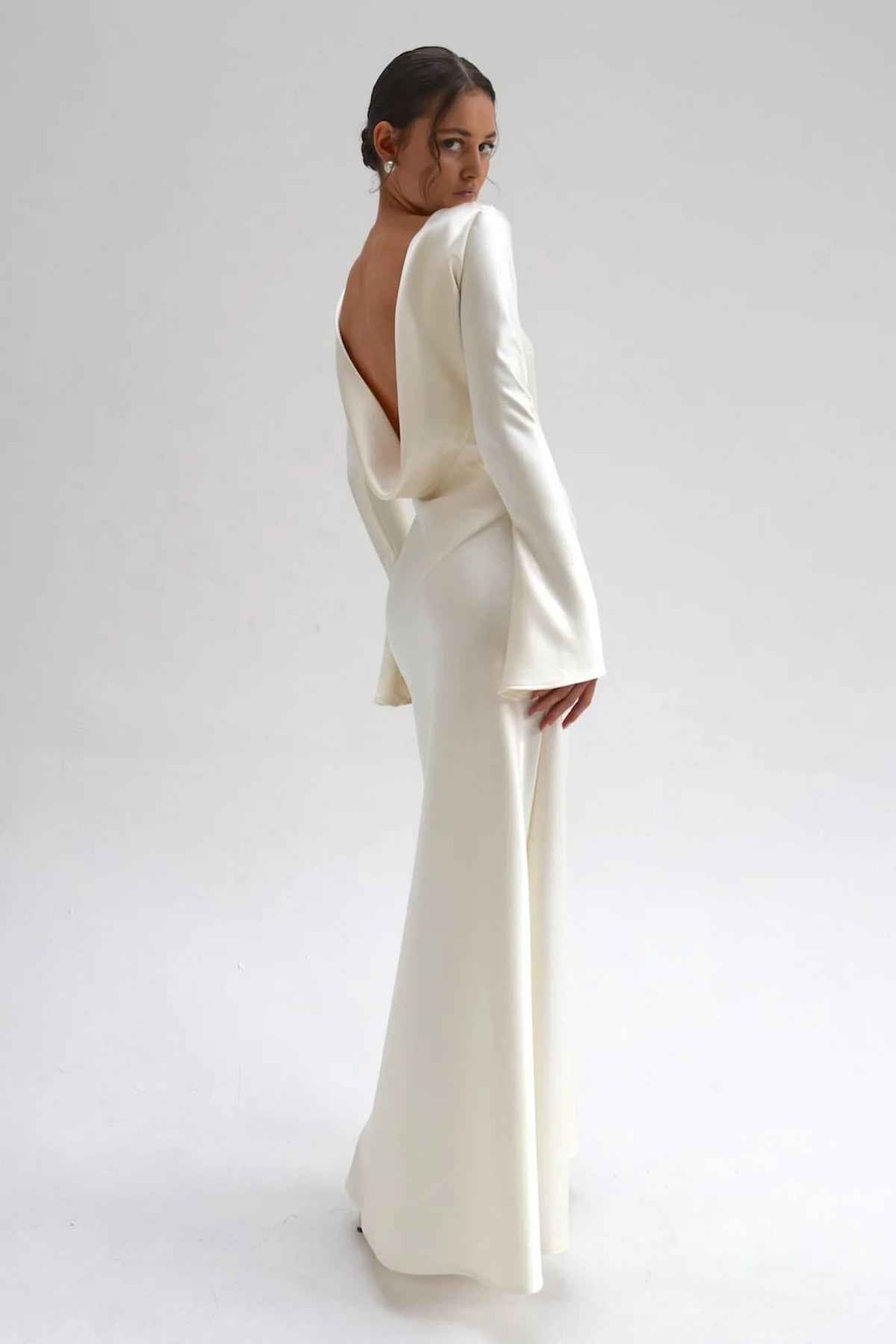 Side-back view of the ivory satin gown showing the draped cowl back and flared cuff