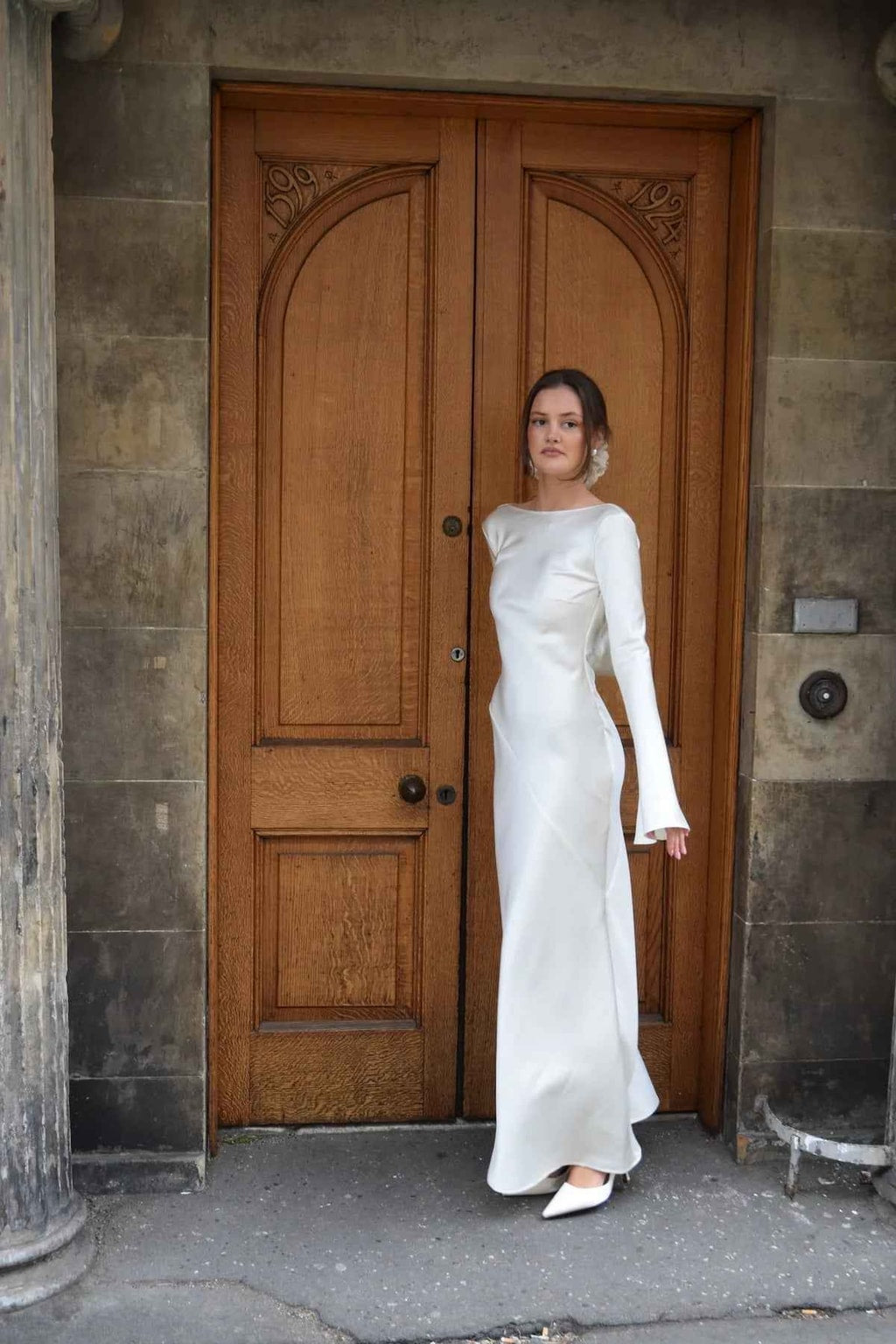 Front view of the ivory satin maxi dress with long bell sleeves, styled with white pointed heels