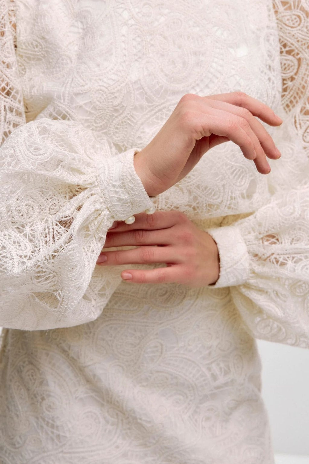 Close-up of the sheer lace sleeves and the narrow cuffs fastened with pearl buttons