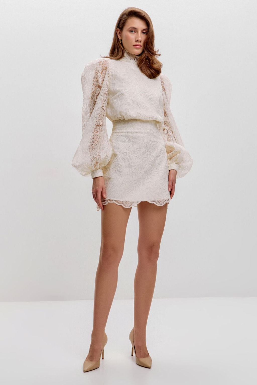 Full-length view of the ivory lace blouse and mini skirt set styled with nude heels