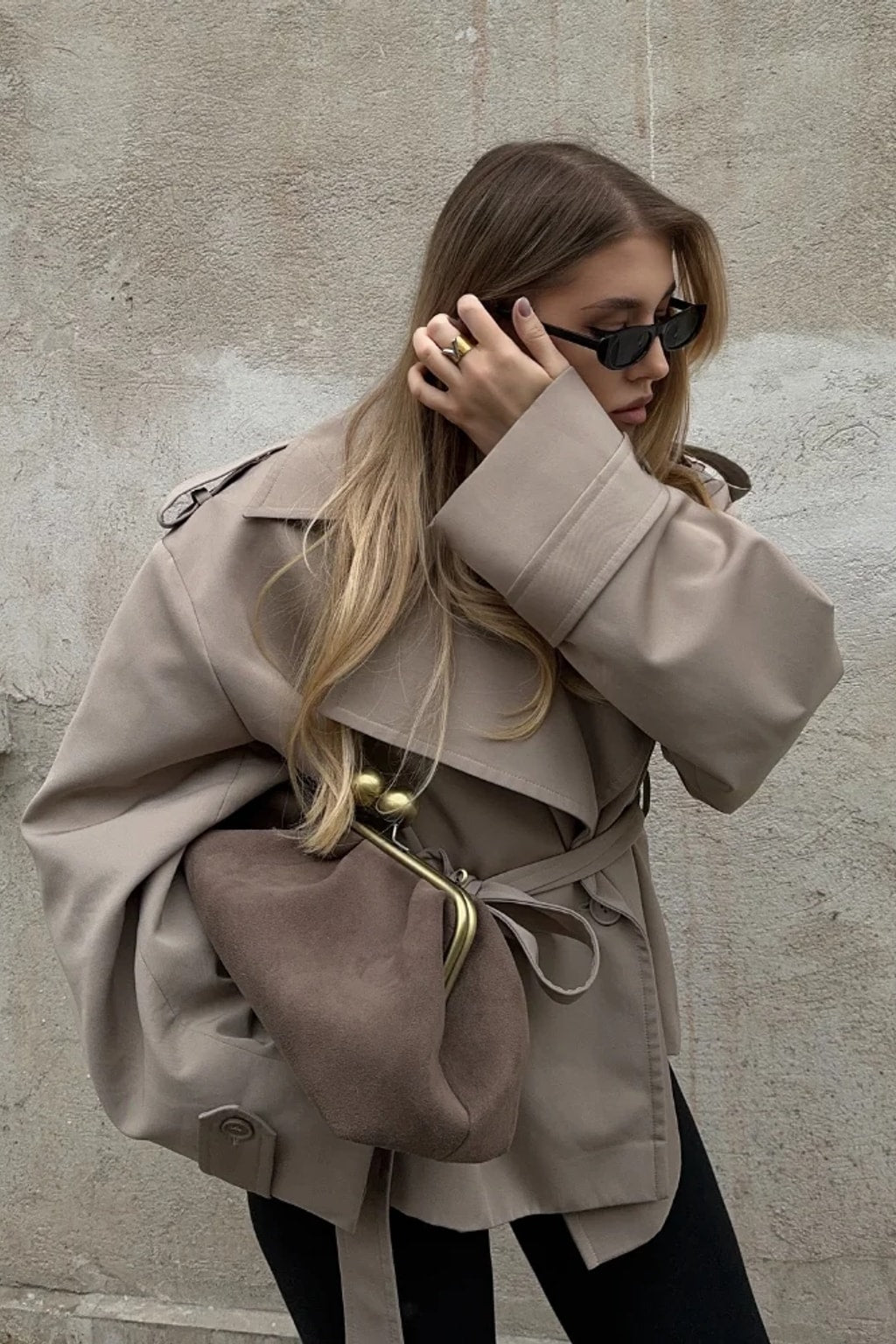 Beige cropped trench jacket that wraps across the front with a self-tie belt, epaulettes and buttoned cuff tabs