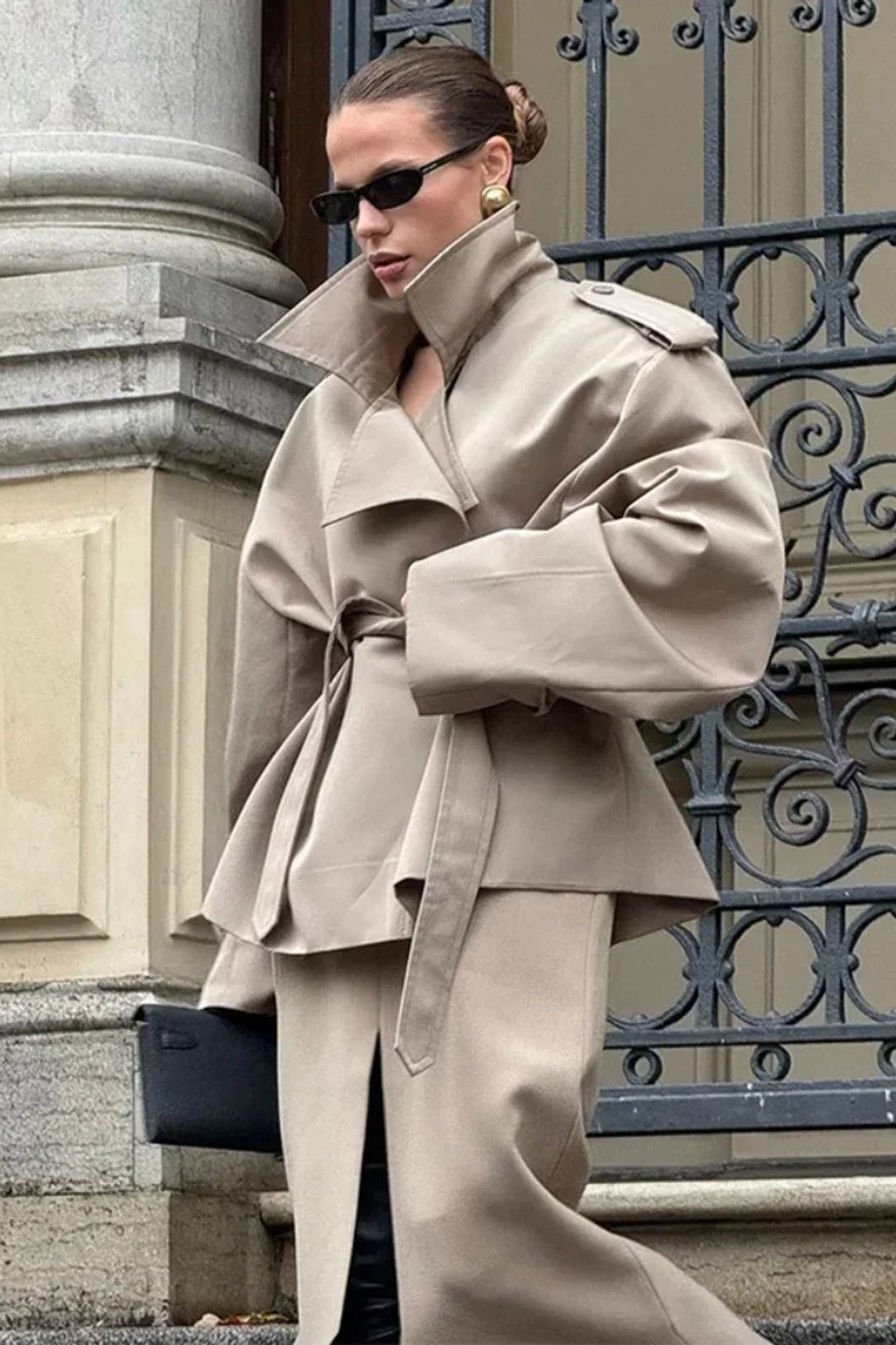 Beige cropped trench jacket that wraps across the front with a self-tie belt, epaulettes and buttoned cuff tabs
