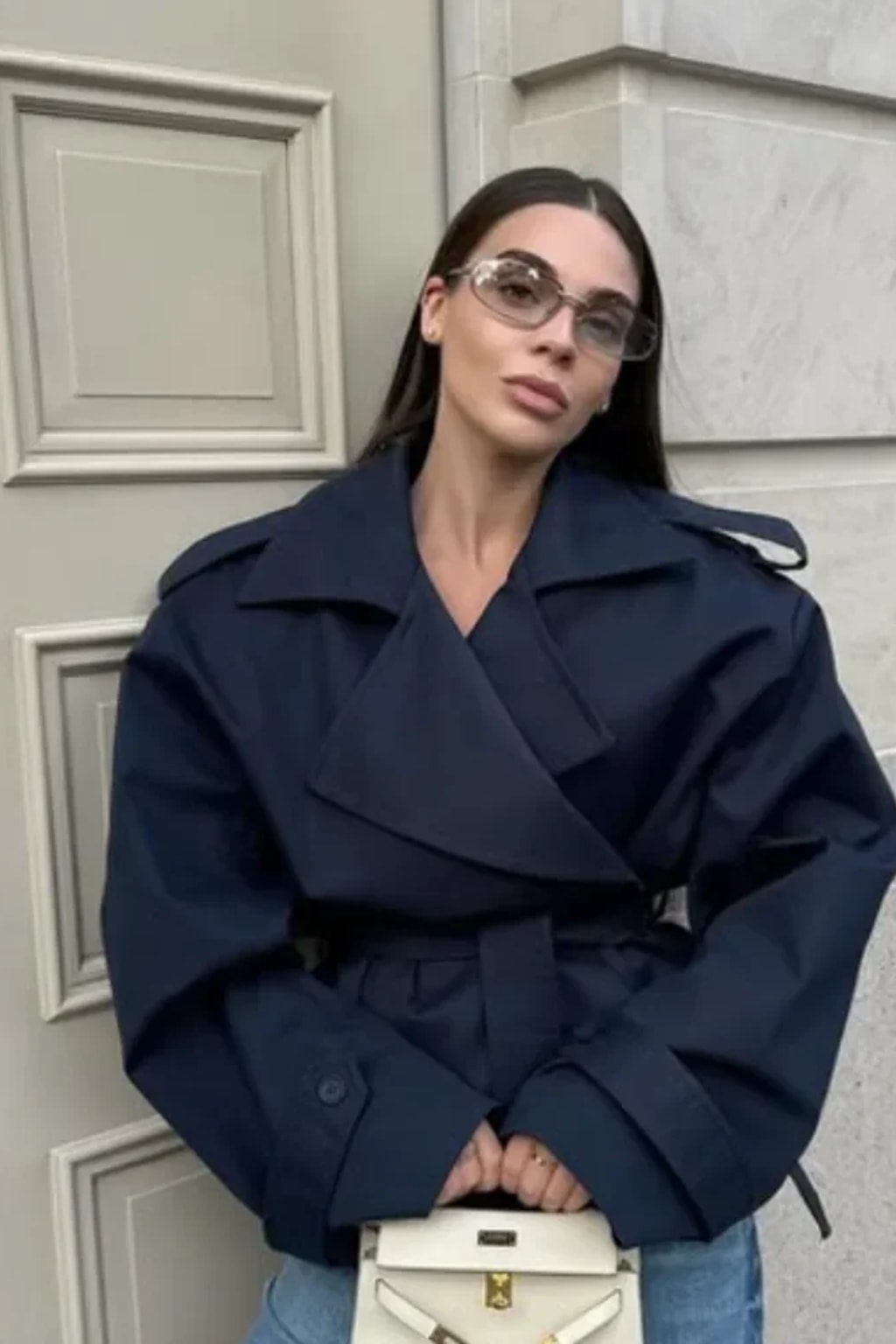 Beige cropped trench jacket that wraps across the front with a self-tie belt, epaulettes and buttoned cuff tabs