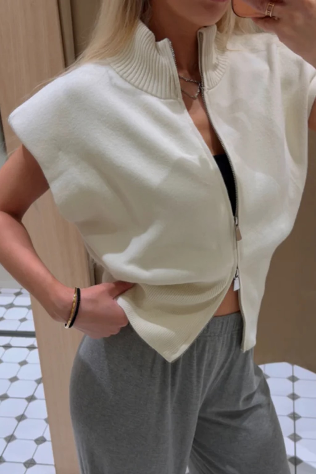 Grey fitted sleeveless knit vest with a high ribbed funnel neck, two-way front zip and structured shoulders
