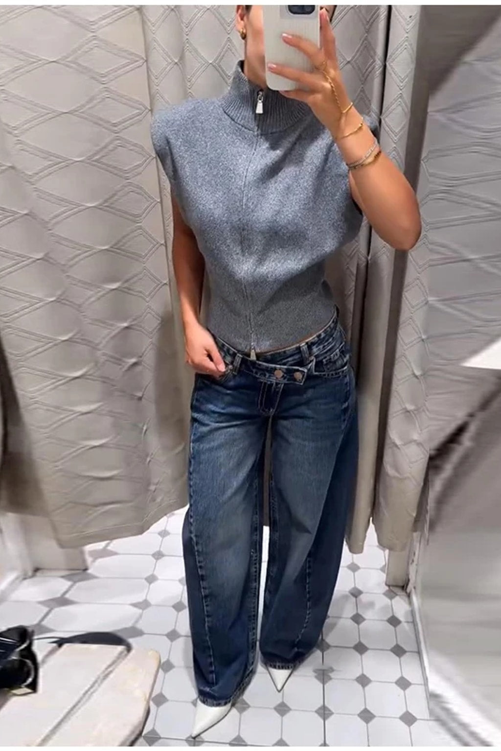 Grey fitted sleeveless knit vest with a high ribbed funnel neck, two-way front zip and structured shoulders