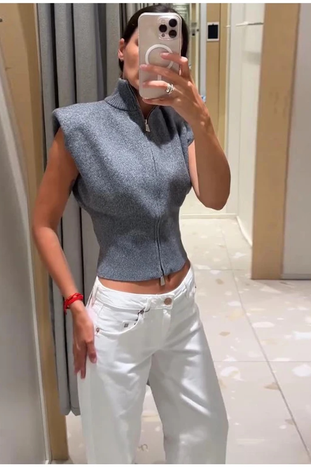 Grey fitted sleeveless knit vest with a high ribbed funnel neck, two-way front zip and structured shoulders