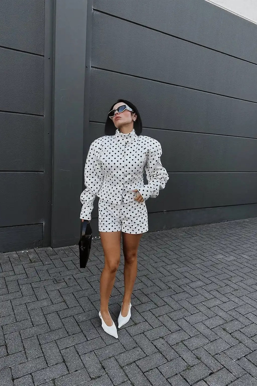 White polka dot fitted jacket with a tall stand collar and structured shoulders with tailored high waist shorts