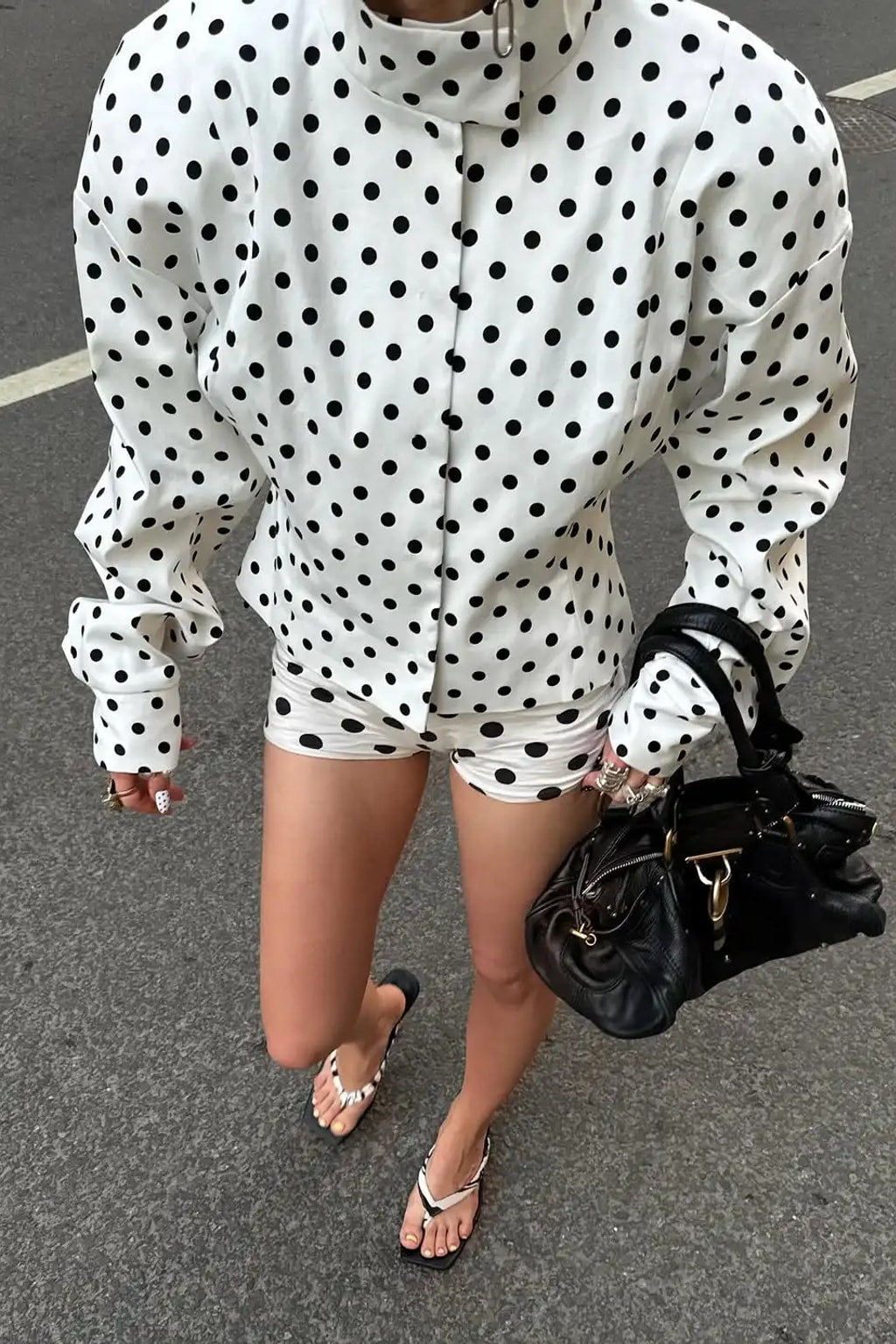 White polka dot fitted jacket with a tall stand collar and structured shoulders with tailored high waist shorts